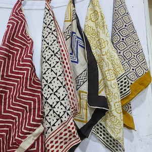 May include: Five fabric squares with different patterns and colors, including red, black, white, blue, and yellow. The squares are hanging on a string.