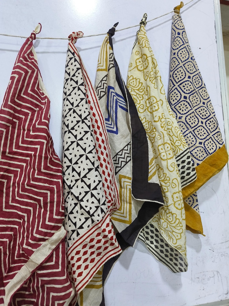 May include: Five fabric squares with different patterns and colors, including red, black, white, blue, and yellow. The squares are hanging on a string.