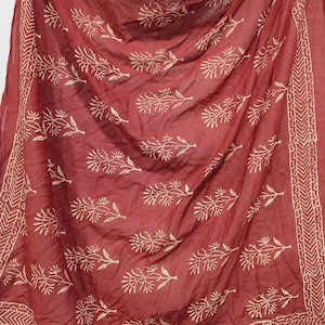 May include: A maroon cotton scarf with a white floral print. The scarf has a white border with a geometric pattern.
