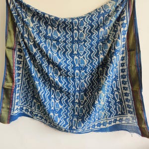 May include: A blue and white patterned textile with a fish motif. The fabric has a wavy design with fish shapes in white against a blue background. The edges are trimmed with gold and red accents.