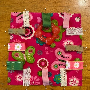 Tags and teething toy pinned to fabric.