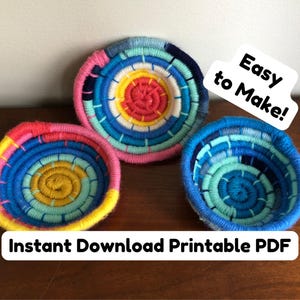 Può includere: Tre ciotole circolari realizzate con filato avvolto in vivaci tonalità di rosa, giallo e blu. Il testo "Easy to Make!" e "Instant Download Printable PDF" è sovrapposto all'immagine. Le ciotole presentano un motivo a spirale e bordi rialzati.