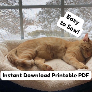 May include: An orange tabby cat sleeping in a round, plush, cream-colored pet bed with a dark blue exterior. The image features white text labels that read "Easy to Sew!" and "Instant Download Printable PDF" overlaid on the scene.