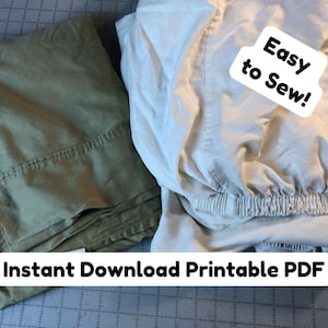 May include: Two folded fabric pieces, one khaki and one off-white, are displayed on a cutting mat. The off-white fabric has an elastic hem. Text on the image reads "Easy to Sew!" and "Instant Download Printable PDF".