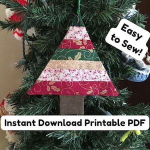 Puede incluir: Adorno de árbol de Navidad hecho a mano con un diseño de patchwork. El árbol es triangular, con franjas alternas de tela roja, verde y beige. El adorno cuelga de un árbol de Navidad verde. El texto en la imagen dice "Easy to Sew!" y "Instant Download Printable PDF".
