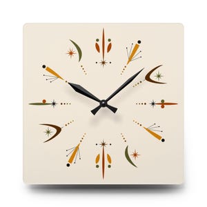May include: Square wall clock with a cream-colored face featuring a mid-century modern design. The clock face has black hands and is decorated with starburst and atomic-age style graphics in shades of brown, orange, and green.