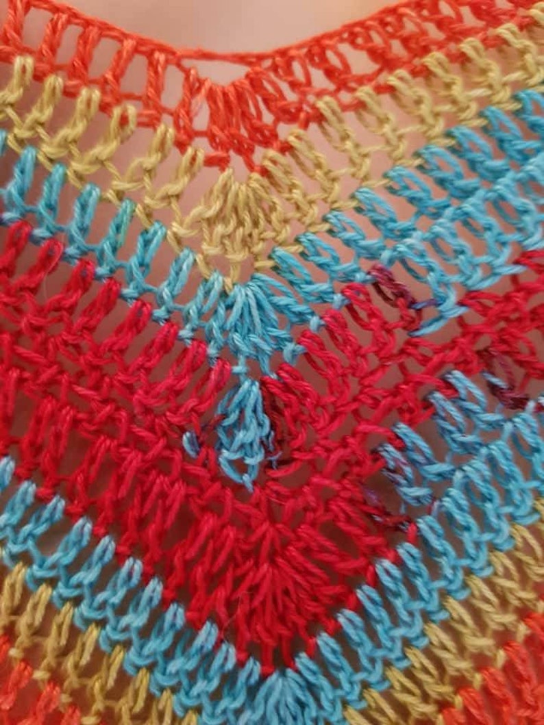 May include: Close-up of a crocheted fabric with a rainbow pattern of orange, yellow, blue, and red.