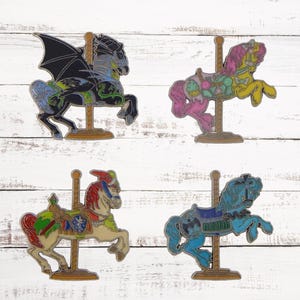Pode incluir: Quatro cavalos de carrossel coloridos, cada um com um design e esquema de cores diferente. Os cavalos são feitos de metal e têm um acabamento detalhado. Eles são montados em uma base de madeira e têm um poste de metal.