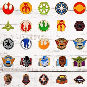 May include: A collection of 25 Star Wars themed enamel pins featuring various characters and symbols from the franchise. The pins are displayed on a white wooden background.