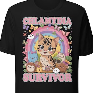 May include: A black t-shirt featuring a graphic print of a central brown tabby kitten surrounded by colorful butterflies, small cartoon creatures, and a rainbow. The text CHLAMYDIA SURVIVOR is printed in large pink letters above and below the illustration.
