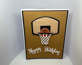May include: A brown and white birthday card with a basketball going through a hoop. The card says "Happy Birthday" in white cursive lettering.
