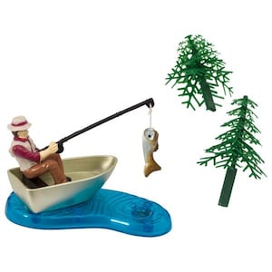May include: A miniature fishing scene featuring a figure in a boat, holding a fishing rod with a caught fish. The boat sits on a blue water base, with two green plastic trees in the background. The figure is wearing a hat and vest.