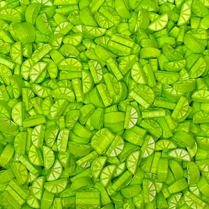 May include: A close-up image of a large quantity of lime green candy sprinkles shaped like lime wedges. The sprinkles are arranged in a random pattern, creating a vibrant and colorful background.