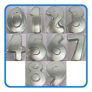 May include: A set of silver-colored number-shaped cake pans, including numbers 0 through 9. Each pan is a different number, with a rounded shape. The pans are arranged in a grid pattern against a white background.