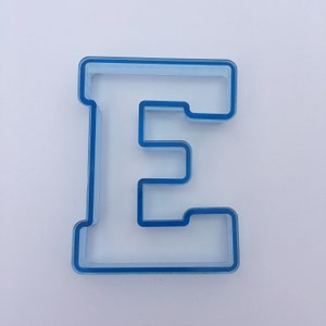 May include: A blue plastic cookie cutter shaped like the letter E.