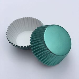 May include: Two cupcake liners, one is teal and the other is white. The teal liner is folded over the white liner.