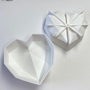 May include: Two white silicone heart-shaped molds. The molds are geometric and have a 3D effect. The molds are open and ready to be used.