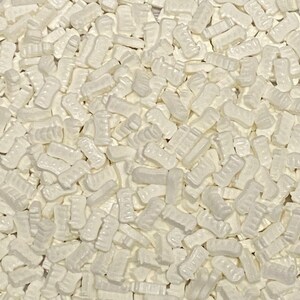 May include: A close-up image of a large quantity of white, pearl-like sprinkles shaped like the letter "I".