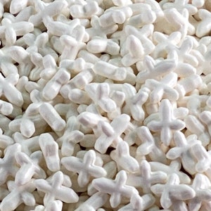 May include: A close-up image of white sugar sprinkles shaped like crosses. The sprinkles are perfect for decorating cakes, cupcakes, and other desserts.