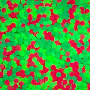 May include: A close-up image of a large quantity of small, round, green and red balls. The balls are arranged in a random pattern and appear to be made of a soft, translucent material.