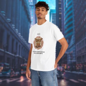 Pode incluir: Uma t-shirt branca de manga curta com um gráfico de uma traça sobre um terminal de computador, com o texto "FACT" e "THE FIRST COMPUTER BUG WAS A REAL MOTH." O design está centrado no peito e a t-shirt é combinada com calças de ganga azuis.
