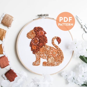 May include: A detailed embroidery hoop art featuring a lion design in shades of orange and brown. The lion is filled with floral patterns and textures, set against a white background. The words "PDF PATTERN" are in a circle. Embroidery floss and scissors are also visible.