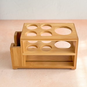 May include: A wooden organizer with two shelves and multiple round cutouts. The organizer is made of light brown bamboo.