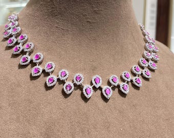 May include: A dazzling necklace featuring a series of pink teardrop-shaped gemstones, each surrounded by a halo of small, clear stones. The necklace is displayed on a mannequin, showcasing its elegant design and sparkle. The necklace is a statement piece.