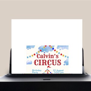 May include: A printed invitation for Calvin's Circus birthday party. The design features a red and white circus tent, blue clouds, and colourful bunting. The text includes the date, 22 August, and time, 3:00 PM.