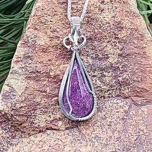 Rare Purpurite stone, framed in a sterling silver wire wrapped setting, suspended on a 18” sterling silver box chain with a lobster clasp.