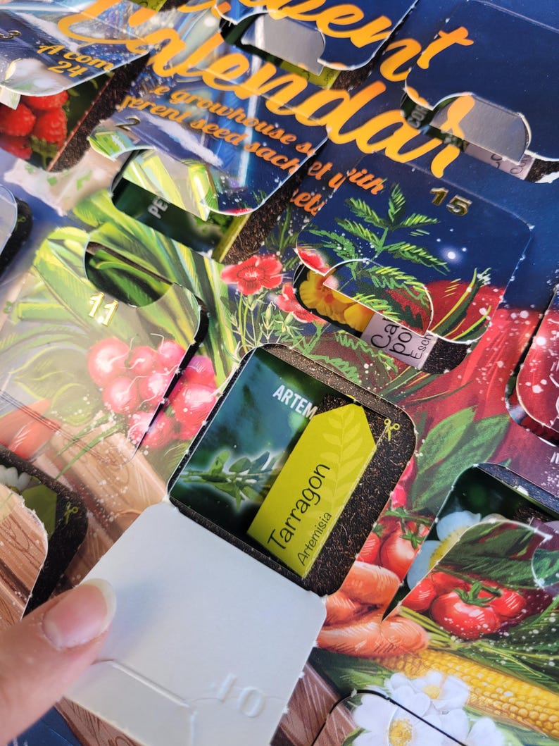 May include: An Advent calendar with open windows revealing seed packets. The calendar has a dark blue background with gold lettering. One window is open, displaying a yellow label that reads "Tarragon Artemisia". Other windows show illustrations of vegetables.