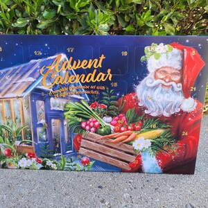 May include: Advent calendar with a Santa Claus illustration holding a wooden crate filled with vegetables. The calendar has a blue background with a greenhouse illustration and the text "Advent Calendar".