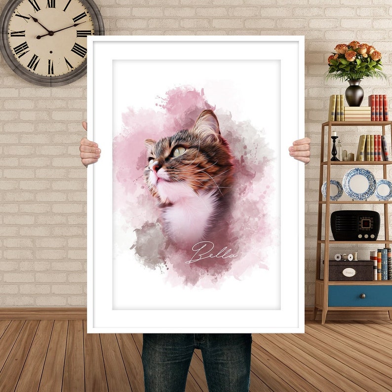 May include: A framed portrait of a cat with brown, white, and gray fur, set against a pink and gray watercolor background. The cat is looking up, and the name "Bella" is written in cursive below the cat's image.