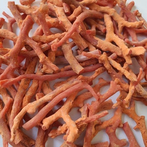 Peut inclure: Un tas de branches de corail orange-rouge, certaines avec plusieurs branches, sur un fond blanc.