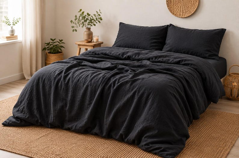 May include: A charcoal black duvet cover set featuring a textured fabric finish. The bedding includes a large duvet cover draped over a bed frame and two matching rectangular pillowcases, creating a uniform dark aesthetic for the sleeping space.