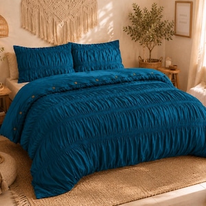 May include: A deep teal duvet cover set featuring a textured, ruched fabric design with horizontal gathered pleats. The duvet cover includes a row of visible buttons along the top edge, paired with two matching rectangular pillow shams in the same color.