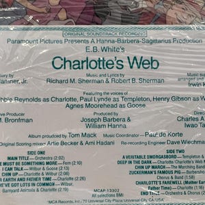 May include: A vintage record album cover for the soundtrack to the movie Charlotte's Web. The cover features a green and white design with the title of the movie in large, bold letters. The album features the voices of Debbie Reynolds, Paul Lynde, Henry Gibson, and Agnes Moorehead. The album was produced by Joseph Barbera and William Hanna and directed by Charles A. Nichols and Iwao Takamoto.