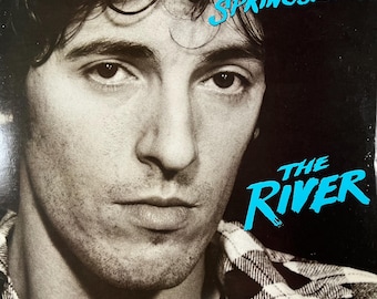 May include: A black and white photo of Bruce Springsteen on the cover of his album "The River". The album title is in blue text.