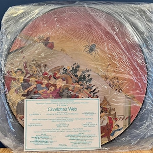May include: A vintage record album cover for the movie Charlotte's Web. The cover features a colorful illustration of the characters from the movie, including Charlotte the spider, Wilbur the pig, and Templeton the rat. The album cover is in a plastic sleeve.
