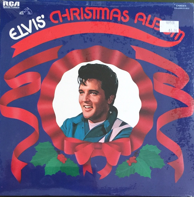 May include: A blue vinyl record album cover featuring Elvis Presley with a red ribbon and holly wreath. The album title is "Elvis' Christmas Album".