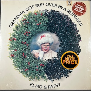 May include: A vinyl record album cover featuring a portrait of an elderly woman inside a wreath of green leaves and red berries. The album title reads "Grandma Got Run Over By A Reindeer" by Elmo & Patsy.