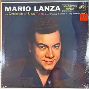 Pode incluir: Um álbum de vinil vintage com Mario Lanza. A capa do álbum apresenta um retrato de Lanza com o texto "MARIO LANZA" e "in a Cavalcade of Show Tunes". O logotipo da RCA Victor é visível.