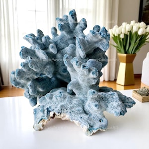 Może przedstawiać: Duża, dekoracyjna rzeźba koralowa w odcieniach niebieskiego i białego. Koral ma teksturowaną powierzchnię ze skomplikowanymi detalami i naturalnym, organicznym kształtem. Rzeźba jest wystawiona na białej powierzchni, sugerując motyw nadmorski lub żeglarski.