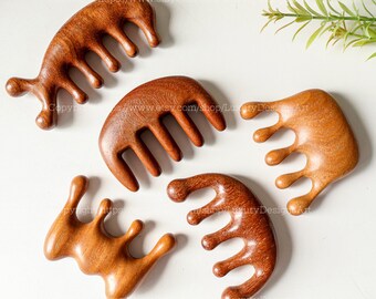 Könnte beinhalten: Vier Holzkämme mit unterschiedlichen Formen und Zahnmustern. Die Kämme sind aus Naturholz gefertigt und haben eine warme braune Farbe.