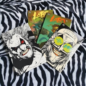 May include: Three comic books featuring the character Lobo. The covers are black and white with red, yellow and blue accents. The text on the covers reads "Lobo" and "The Wisdom of Pain".
