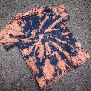 May include: A tie-dye t-shirt with a black and orange swirl pattern.