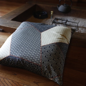 Puede incluir: Un cojín con estampado en blanco y negro con un diseño geométrico. El cojín está hecho de tela y tiene una textura suave y cómoda.