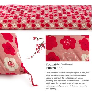 May include: A rectangular futon mattress featuring a Koubai red plum blossom pattern with pink, red, and white floral motifs on a pink background. The fabric displays a repeating print of stylized plum blossoms with visible stitching details.
