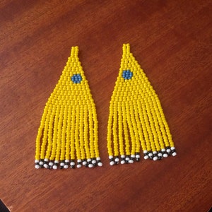 May include: A pair of yellow beaded earrings with a blue center and black and white trim.