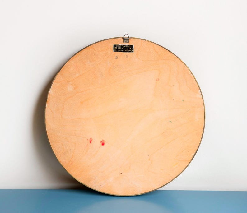 May include: The back of a round, wooden wall mirror with a brass frame. The mirror has a label that reads "Eurotravel Braun, K&ouml;ln-Deutz, Germany".